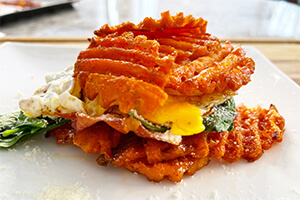 a fried egg, crispy prosciutto, melted Gruyère and sautéed baby spinach layered on a bed of Alexia waffle cut sweet potato fries